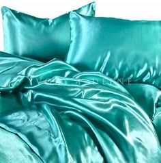 a bed covered in green sheets and pillows