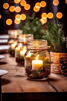 several jars filled with candles sitting on top of a wooden table covered in pine cones