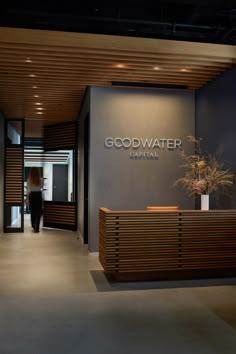 an entrance to a building with a plant in the center and a sign that says good water capital