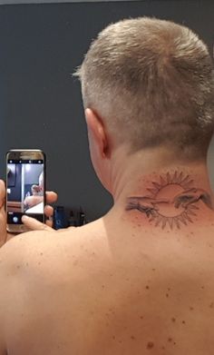 a man with a tattoo on his neck taking a selfie in front of a mirror