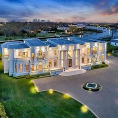 an aerial view of a large white mansion at night with lights on the front and side windows