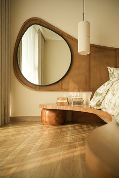 a bed room with a neatly made bed and a large round mirror on the wall