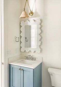 a bathroom with a sink, toilet and mirror on the wall in it's corner