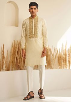 Presenting the Ivory And Gold Silk Kurta Set with a chinese collar for elegance and metallic golden buttons for a unique detail. The hand embroidered details on the neckline and cuffs make it stand out. Teamed with elegant white pants. Perfect for an Engagement, Roka or Wedding Reception. Composition : Chanderi Silk Care: Dry Clean Only and Vacuum Storage This product can be customized for sleeves, length and colour Delivery : 4-6 weeks as the product is hand crafted. Check Size Guide or choose MySize for free customisation (All Sizes above XL can be made at 15% additional cost) For more information and sizes please contact fabiliciousfashion@gmail.com or visit our Copenhagen studio. About the Designer : Shreyansh, a distinguished designer label specializing in luxurious ethnic menswear fo Traditional Festive Sets With Embroidered Neckline, Elegant Festive Traditional Wear With Embroidered Neckline, Traditional Sets With Embroidered Neckline For Festivities, Festive Traditional Wear With Embroidered Neckline, Festive Embroidered Neckline Traditional Wear, Wedding Sets With Embroidered Neckline For Eid, Traditional Designer Kurta With Embroidered Cuffs, Designer Long Sleeve Kurta With Embroidered Cuffs, Designer Embroidered Cuff Kurta For Eid