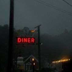 a sign that says diner on it in the dark foggy night with street lights