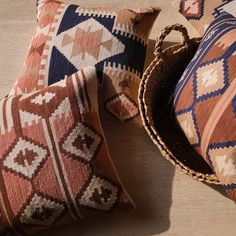 three pillows and a basket on a wooden floor, one is made out of woven material