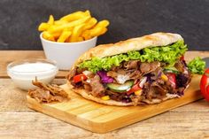 a cut in half sandwich sitting on top of a cutting board next to french fries