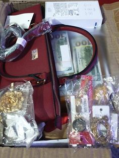 a red purse sitting inside of a box filled with money