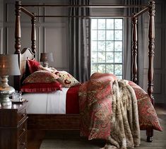 a bedroom with a four poster bed and red comforter on top of the bed