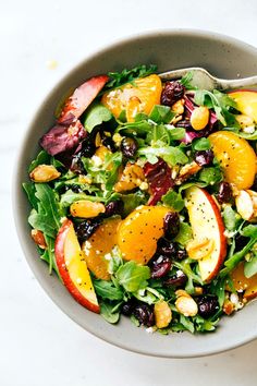 a salad with apples, oranges and raisins in a bowl on a table