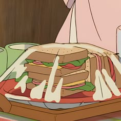 a person cutting into a large sandwich on top of a wooden table next to a glass of milk