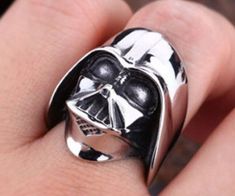 a person wearing a star wars helmet ring on their finger, with the face of darth vader printed on it