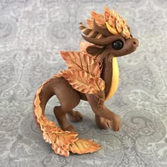 a figurine of a dragon with orange leaves on it's tail