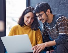 a man and woman looking at a laptop