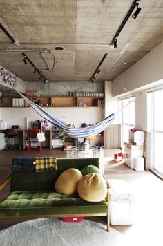 a hammock hanging from the ceiling in a living room with green couches