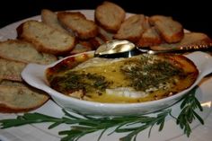 a white plate topped with bread and an egg in a bowl next to garlic bread