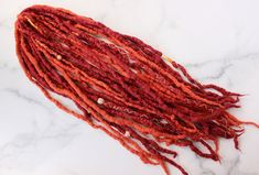 "Wildfire" * 100% merino wool dreadlocks * Color : Sangria red and papaya orange > READY TO SHIP - mails out in 3-6 business days 17 - double ended dreadlocks, averaging 18 inches length (when folded in half - the length they'll be when installing) Decorated with cotton thread wrappings and wood beads. Since I make each dreadlock by hand, there is some variation in thickness. There may be a mix of some microlocs (2/8 inch), a few thick locs but overall I try to keep an average thickness of around 3/8 - 1/2 inch for majority of the locs. . . . . . . . . . FAQ's > How many do I need? For a partial set or if you have a mohawk, anywhere from 20 - 30 DE or 30 SE. For a full head set, anywhere from 40 - 50+ DE, or 50 - 60 SE. How many you need depends on how thick your hair is, and how much of y Sangria Red, Thick Locs, Wool Dreadlocks, Cotton Decor, Red Sangria, Strand Braid, Easy Braids, Medium Long