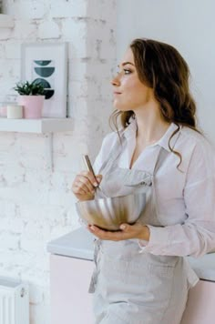 a woman in an apron holding a metal bowl