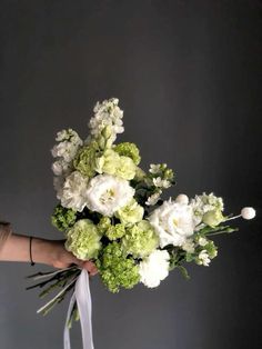 a person holding a bouquet of white and green flowers