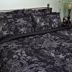 a black and white comforter set on a bed with flowers in the background,