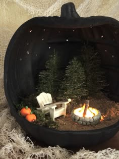 a miniature pumpkin shaped like a chair and fire in the ground with small trees inside