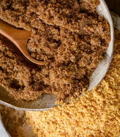 a wooden spoon in a metal bowl filled with brown sugar and crumbled breadcrumbs