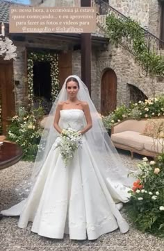 a woman standing in front of a building wearing a wedding dress