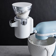 a white and blue blender sitting next to each other on top of a table