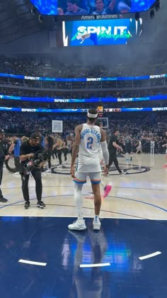 a man standing on top of a basketball court in the middle of a crowd at a sporting event