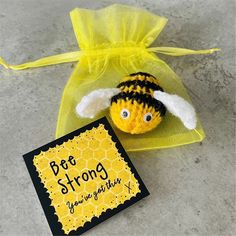 a small stuffed bee sitting on top of a yellow bag next to a greeting card