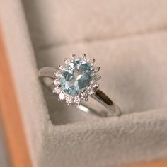 an engagement ring with a blue topaz surrounded by white diamonds in a velvet box