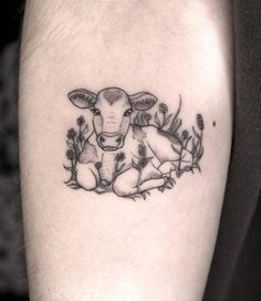 a small cow tattoo on the left calf's leg, with flowers around it