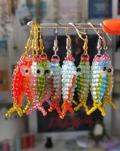 four fish shaped beaded earrings hanging from a hook on a rack in a store