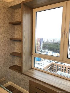 there is a window in the corner of this room with shelves on both sides and a city view outside