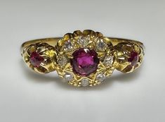 an antique ring with three different colored stones in the center and two smaller round diamonds on each side