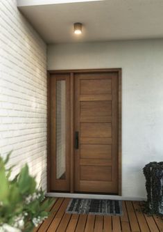 a wooden door on the side of a white brick wall next to a potted plant