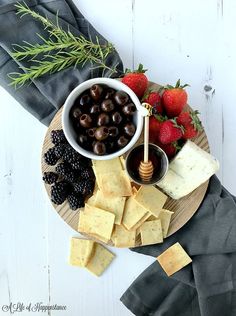 a cheese board with berries, olives, and crackers on the side for dipping