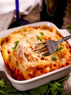 a fork in a casserole dish with cheese and parsley on the side