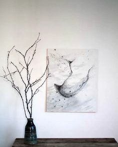 there is a vase with branches in it next to a painting on the wall above