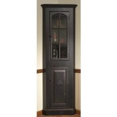 a tall wooden cabinet with glass doors on the top and bottom shelf, in an empty room