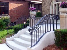 a wrought iron stair railing next to a brick building with potted plants on it