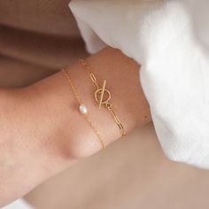 "This bracelet features a small toggle closure on a dainty paperclip gold chain that measure 2 mm wide and can be made to fit your wrist snugly. Toggle measures 9mm wide. Be sure to measure your wrist if you are going for a tight fit like the model who is wearing the 5.75 inches. Otherwise, the standard length at department stores for women's bracelets is 7 inches. This item is 14k gold filled and is tarnish-resistant, water-resistant, and hypoallergenic. --------------------♥ PROMOS ♥---------- Classic Bracelets With Lobster Clasp As Gift, Classic Bracelets With Lobster Clasp For Gifts, Elegant Gold Bracelet With Toggle Clasp, Elegant Oval Link Bracelet For Gifts, Elegant Sterling Silver Bracelet With Clasp For Gift, Classic Chain Bracelet With Toggle Clasp, Modern Sterling Silver Bracelet With Toggle Clasp Gift, Timeless Adjustable Chain Bracelet With Oyster Detail, Adjustable Formal Chain Bracelet With Clasp