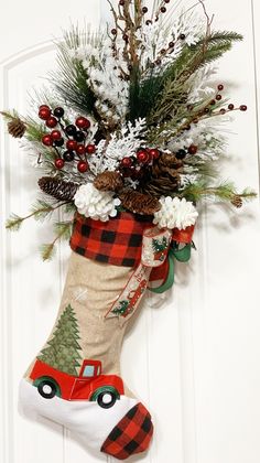 a christmas stocking hanging on the front door with pine cones, berries and evergreens