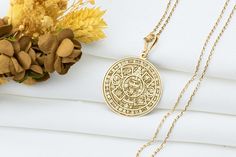 This stunning necklace is inspired by the Tōnalpōhualli, the sacred Aztec calendar and the iconic Sun Stone, which symbolizes the cosmic order and the cyclical nature of time. The Tōnalpōhualli was used to guide daily life, rituals, and spiritual practices, representing the intricate connection between humanity and the cosmos. At its center is the face of Tonatiuh, the Aztec sun god, who embodies vitality, renewal, and the eternal energy of life. Wearing this Tōnalpōhualli Sun Stone necklace is Symbolic Medallion Jewelry For Ceremonial Occasion, Symbolic Ceremonial Medallion Jewelry, Symbolic Ceremonial Necklace With Locket, Symbolic Ceremonial Locket Necklace, Engraved Amulet Medallion Necklace, Symbolic Locket Necklace For Ceremonial Use, Symbolic Pendant Necklace For Rituals, Symbolic Necklaces With Intricate Design, Engraved Round Pendant For Rituals