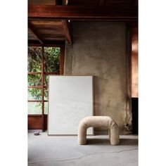 a chair sitting on top of a cement floor next to a large white piece of art