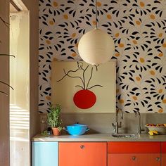 a kitchen with an orange cabinet and blue bowl on the counter next to a painting