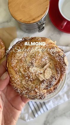 a person holding a pastry with powdered sugar on top