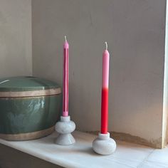 two candles sitting on top of a white mantle