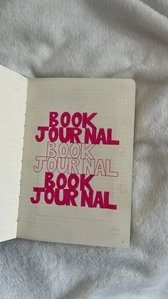 an open book with the words journal written in red on it, sitting on a bed