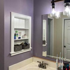 a bathroom sink sitting under a mirror next to a white cabinet and light above it